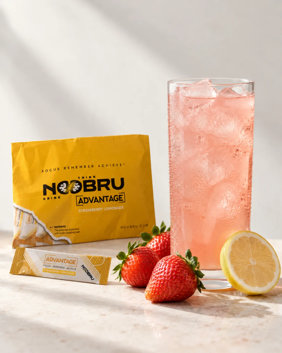 Noobru Advantage envelope and sachet beside a glass of strawberry-pink drink with strawberries and lemon